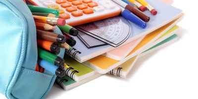 Various school supplies including notebooks, calculator and pencil case isolated against a white background